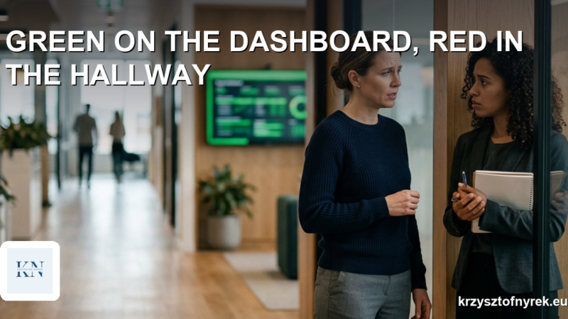 Two colleagues talking in an office hallway with a green project dashboard in the background